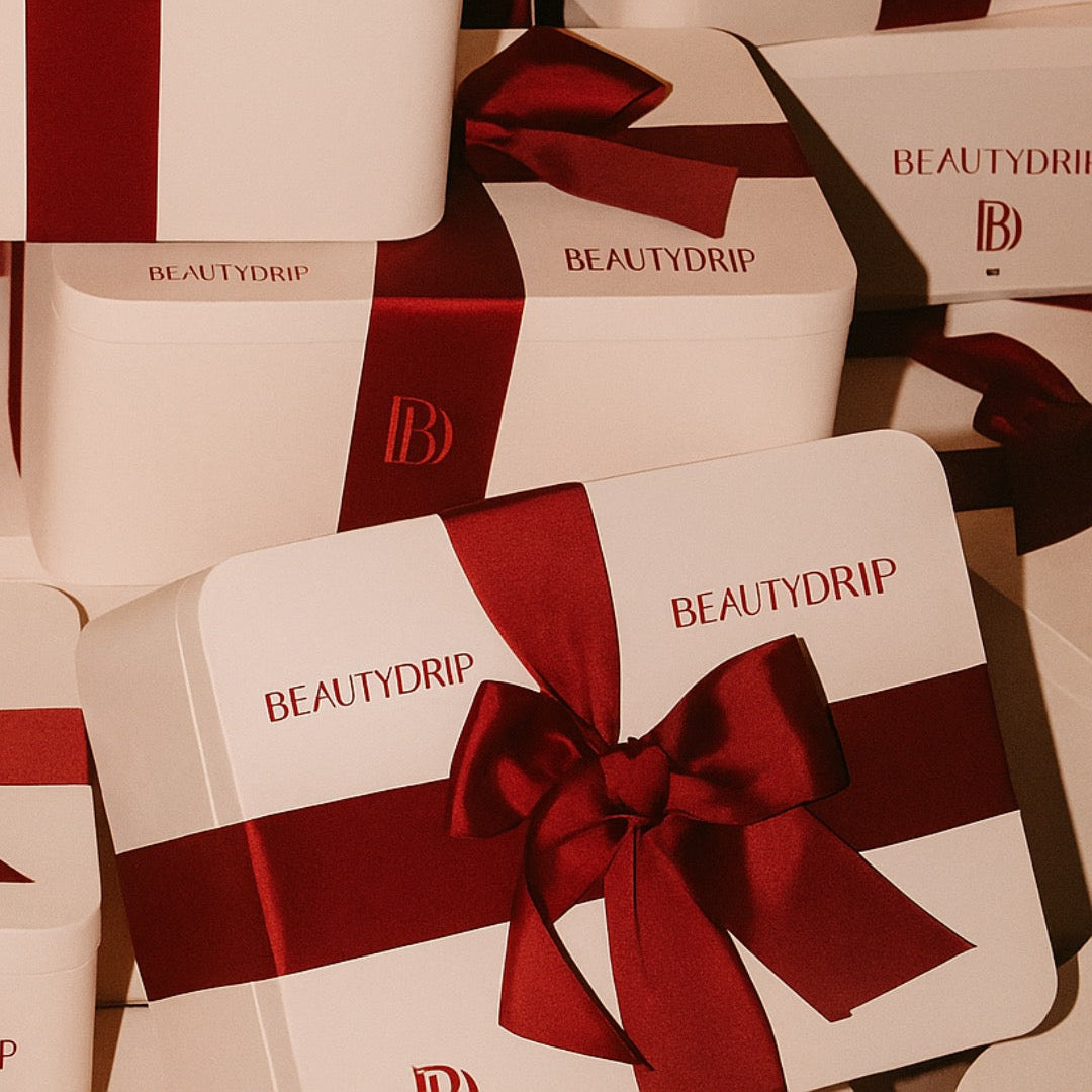 Multiple Beautydrip boxes with red ribbons on a matching background