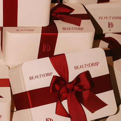 Multiple Beautydrip boxes with red ribbons on a matching background