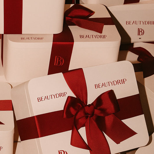 Multiple Beautydrip boxes with red ribbons on a matching background